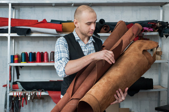Man in leather workshop, examines the skin roll leather.