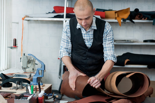 a master in the workshop, carefully examining the leather rolls.