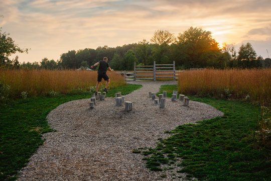 Distant-view of a man running through an obstacle course at sunset