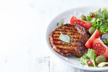Grilled pork steak with fresh salad. White wooden background. Copy space.	
