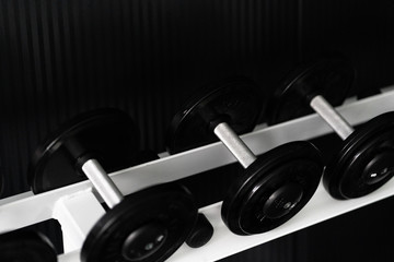 Obraz na płótnie Canvas Black dumbbell set. Close up many metal dumbbells on rack in sport fitness center , Weight Training Equipment concept.Indoor gym training for fitness activity or bodybuilders.