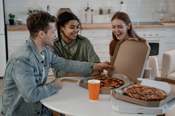 Pizza lovers, student resting at home, have little pretty time, eat and drink, food delivery. International friendship, happy time together, friends having relax time. Enjoy communication and holiday.