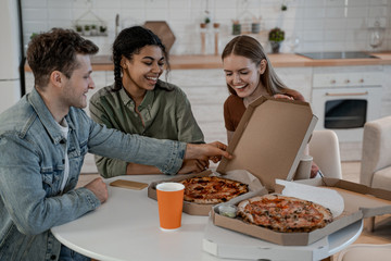Pizza lovers, student resting at home, have little pretty time, eat and drink, food delivery. International friendship, happy time together, friends having relax time. Enjoy communication and holiday.