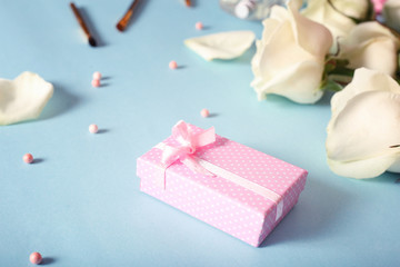 Box with a gift, cosmetics and flowers and on a blue background