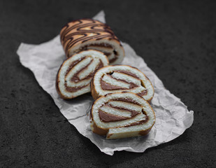 Cake roll chocolate cream on a dark background