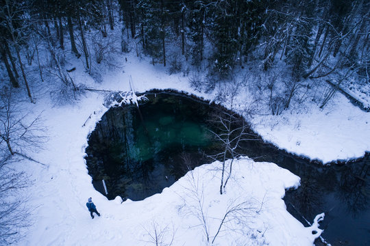 Aerial view of a man watching a water spring surrounded by snow Siniallikad Saula, Harju County, Estonia