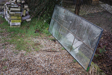 a broken, old window in the yard is waiting for waste disposal and recycling
