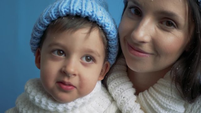 mother and son in blue knitted warm hats and white sweaters in the snow