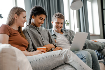 Happy group of students at home working on a joint project for the university. International friendship, happy time together, friends having relax time. Enjoy communication and holiday.