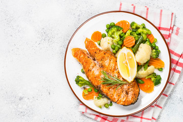 Grilled salmon fish steak with vegetables on white.