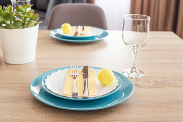 Beautiful Easter Table Setting With Decorations. Blue Plates On Yellow Feeding Mats. Yellow Easter Painted Eggs