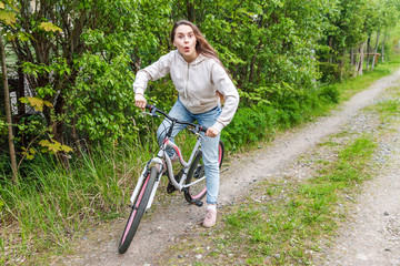 Fototapeta na wymiar Young woman riding bicycle in summer city park outdoors. Active people. Hipster girl relax and rider bike. Cycling to work at summer day. Bicycle and ecology lifestyle concept
