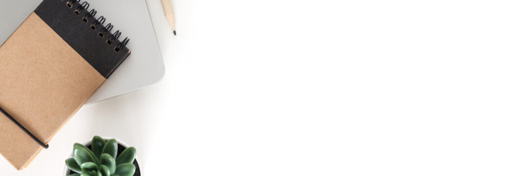 White desk in the office. View from above. Notebook and plant. Copy space. Panorama