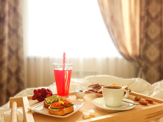 Tasty homemade breakfast in a white bed in the bedroom.