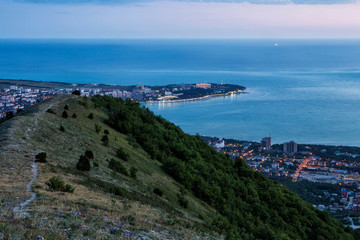 Fototapeta na wymiar Gelendzhik Bay, Thick Cape and Gelendzhik lighthouse in the evening twilight from a bird's eye view. lights of the embankment are reflected in the Bay.