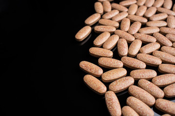Pills on a black background on the right side of the frame, place for text, top view
