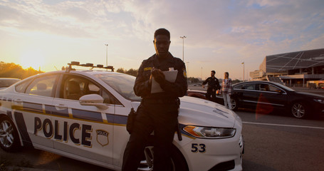 Portrait of attractive concentrated young black man police officer doing paperwork near the police...