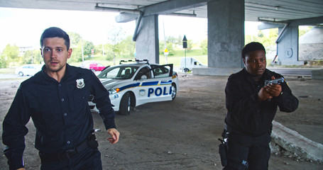 Danger in the city. Hurrying professional armed police officers run out of patrol car to the crime scene. Cops in action. © Fractal Pictures