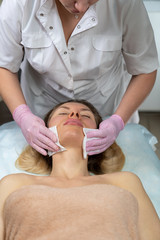 Beautician makes a procedure for a girl to improve facial skin condition