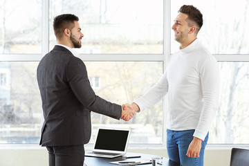 Bank manager and man shaking hands in office