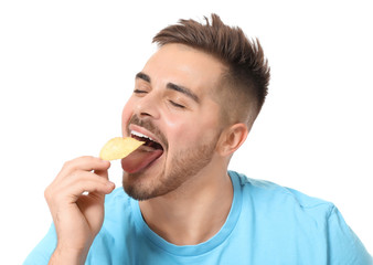 Handsome young man eating tasty potato chips on white background
