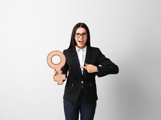 Young business lady holding symbol of woman on grey background