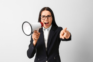 Screaming business woman with megaphone on light background. Concept of feminism