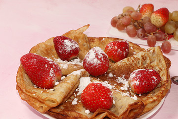 Pancakes with strawberries on a pink sunny background. The concept of healthy and natural food. Healthy breakfast, food for children. selective focus. Traditional Russian pancakes and Shrovetide