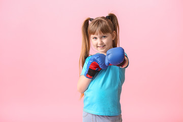 Little girl in boxing gloves on color background. Concept of feminism