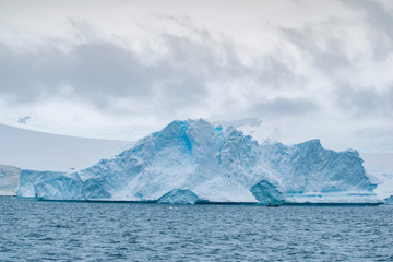 Man on a small rubber boat next to iceberg floating in the ocean. Antarctic Peninsula