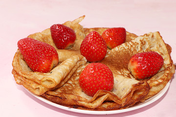 Pancakes with strawberries on a pink sunny background. The concept of healthy and natural food. Healthy breakfast, food for children. selective focus. Traditional Russian pancakes and Shrovetide