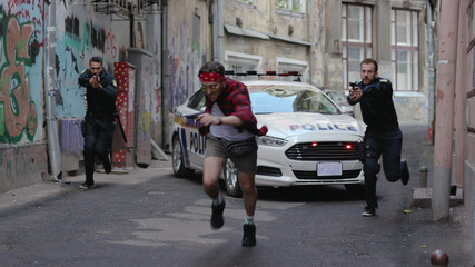 Two policemen run for a criminal pistol arrest bad guy street city crime danger dangerous gangster...