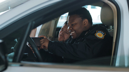 Funny two policemen eating donut use phone smile talk sitting in patrol car help happy african american break rest gangster uniform funny teamwork portrait slow motion