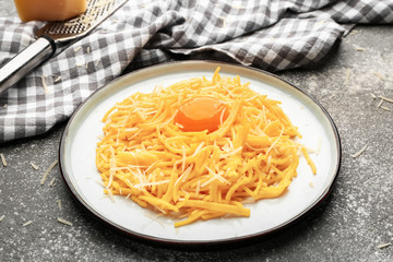 Plate with tasty pasta, cheese and egg on grey background