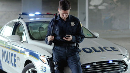 Policeman cops stand near patrol car use phone accepting emergence call enforcement talk officer...