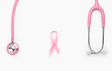 Fototapeta premium Pink ribbon with stethoscope on white background. Breast cancer awareness concept
