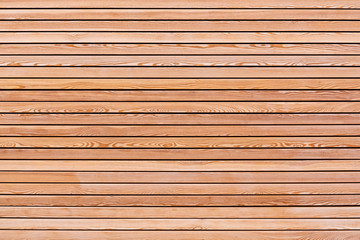 A solid wall of brown wooden planks arranged horizontally. Concept for texture, background, interior