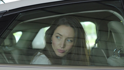 Sad young woman arrested by police officers and handcuffed sitting in patrol car criminal handcuffs...