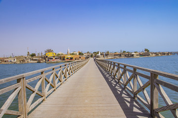 Fototapeta na wymiar Long wooden bridge leading over a sea lagoon. It leads to Fadiouth Island in Senegal, Africa. It is a beautiful natural background.