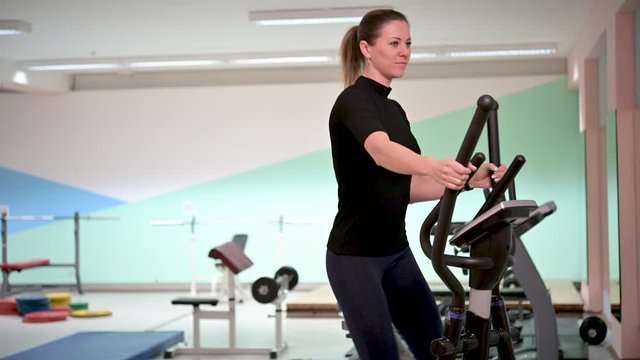 Beautiful girl run orbitrek gym body fitness concept. Fitness and healthy lifestyle concept. Sportswoman using run machine in fitness center.