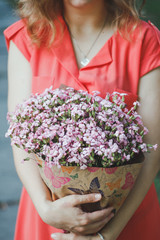 girl in a red dress holds a bouquet of flowers in her hands