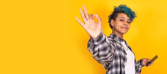 trendy young girl with mobile phone isolated on yellow background