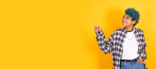 young afro american girl isolated on yellow background pointing by hand