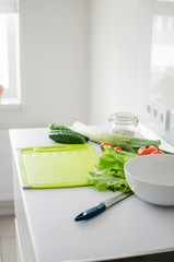 Bowl with salad and fresh vegetables on kitchen table. Healthy food