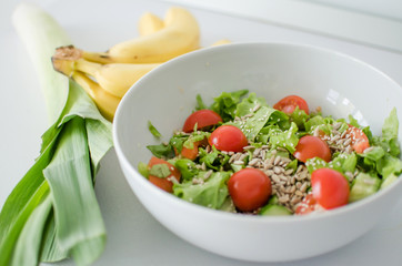 Bowl with salad and fresh vegetables on kitchen table. Healthy food