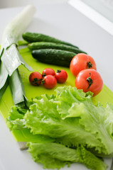Bowl with salad and fresh vegetables on kitchen table. Healthy food