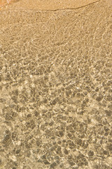 Rocky beach and rippled clear water viewed from above. Abstract natural full frame image.