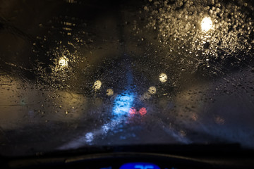 Fototapeta na wymiar Rain water on a car windscreen affecting road visibility inside a dark tunnel road