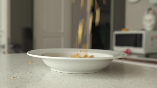 Corn flakes falling into a plate, 4K
