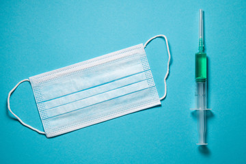 Green antidot in syringe and medical mask. Antivirus vaccine concept.